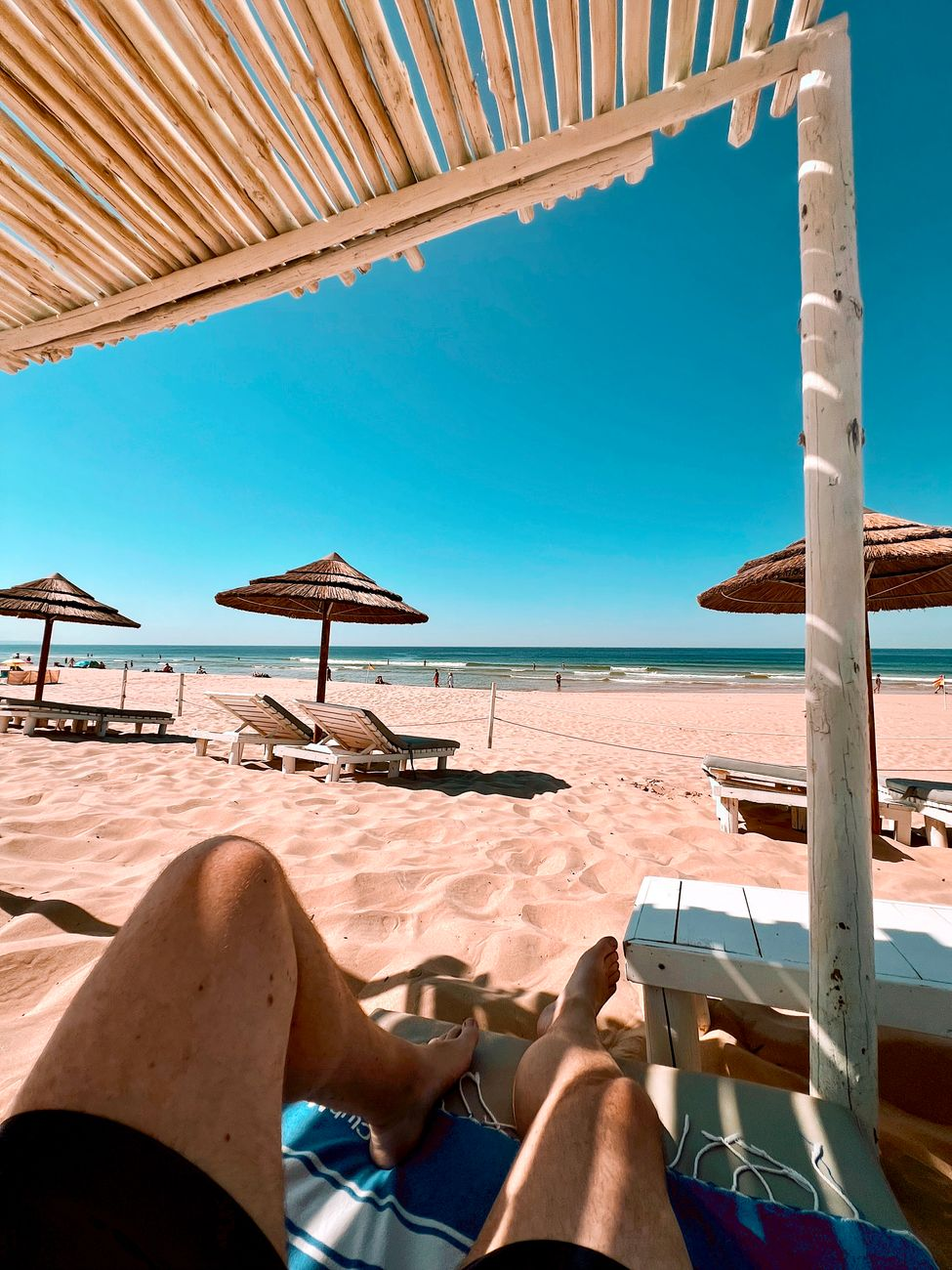relaxing beach day under straw umbrella